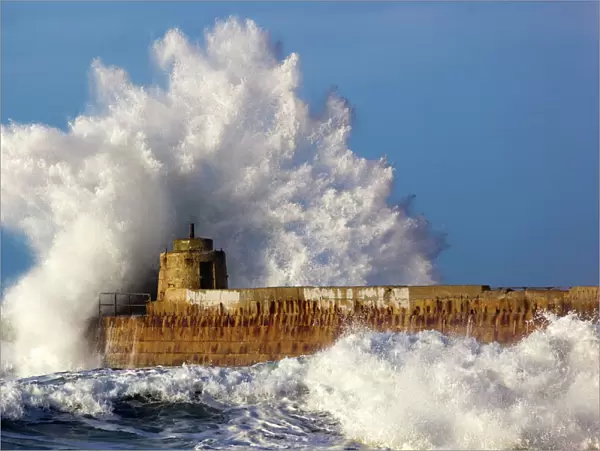 Portreath - wave breaks over pier in storm - Cornwall - UK