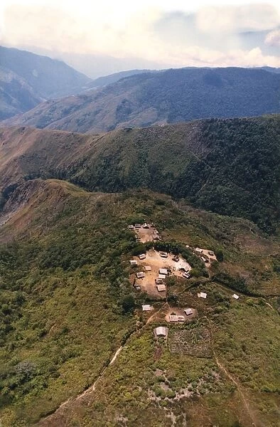 An aerial view of villagers congregating in the village square of a remote mountain village in Morobe Province, Papua New Guinea. The steep walk-track on the second ridge connects to the village on the top of that ridge