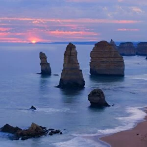 Twelve Apostles sunset - setting sun over the sandstone rock formations of famous Twelve Apostels, which are sculpted by the relentless sea. The force of the sea eats more and more of the rocks away and finally forces them to collapse