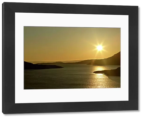Sunset over Loch Broom with sun still up casting red light over water and mountain ridges around the Loch Loch Broom near Ardmair, Wester Ross, Highlands, Scotland, UK