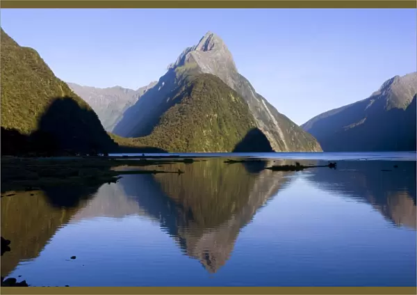Milford Sound landmark Mitre Peak and surrounding mountains reflected in the calm waters of Milford Sound in early morning. Milford Sound is one of the, if not THE, most famous attraction in New Zealand