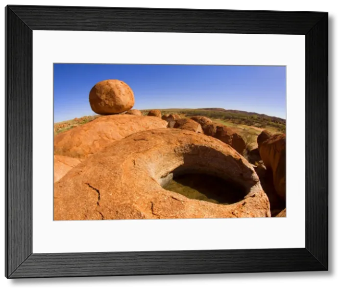 Framed Print : Devils Marbles - a nearly perfectly circular shaped boulder of red granite is balanced on a hugh rock with a small crevice filled with water - Devils Marbles Conservation Area, Northern Territory, Australia Framed Print : Devils Marbles - a nearly perfectly circular shaped boulder of red granite is balanced on a hugh rock with a small crevice filled with water - Devils Marbles Conservation Area, Northern Territory, Australia