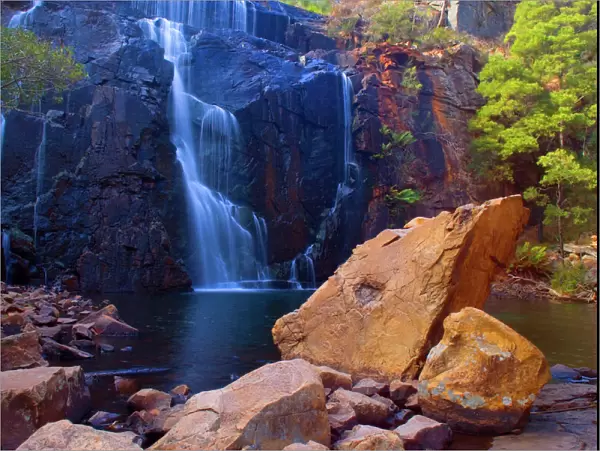 Mac Kenzie Falls - water cascades down red cliffs of Mac Kenzie Falls into a picturesque plunge pool surrounded by gum trees and hugh boulders - Grampians National Park, Victoria, Australia