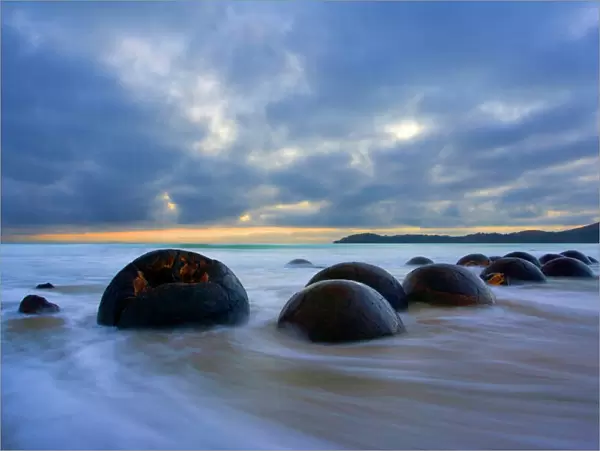 Moeraki Boulders - massive spherical rocks at dawn surrounded by water of incoming tide Coastal Otago, South Island, New Zealand