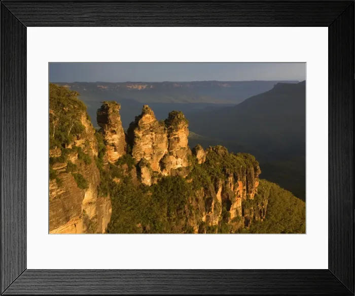 Framed Print : The Three Sisters - famous sandstone formations Three Sisters, seen from Echo Lookout, at sunset. The low sun finds a hole in the heavily clouded sky and plunges exactly the Three Sisters in exquisite red light - Blue Mountains National Park Framed Print : The Three Sisters - famous sandstone formations Three Sisters, seen from Echo Lookout, at sunset. The low sun finds a hole in the heavily clouded sky and plunges exactly the Three Sisters in exquisite red light - Blue Mountains National Park