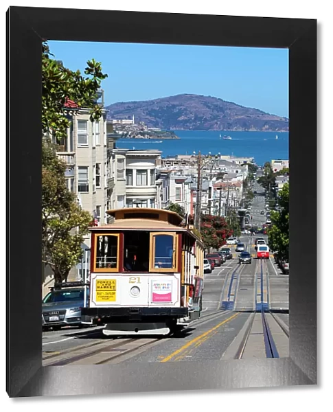 13132534. Street scene with a Cable Car tram and Alcatraz Prison island in San Franciso
