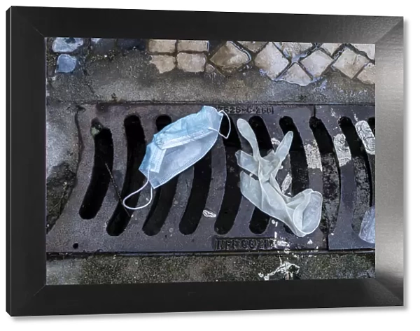 13132595. Mask and surgical gloves on top of urban sewer grid