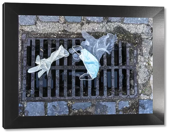13132596. Mask and surgical gloves on top of urban sewer grid
