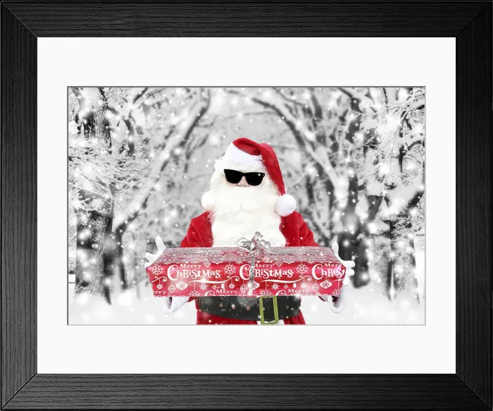 Framed Print : Father Christmas  /  Santa Claus wearing sunglasses holding Christmas present in winter snow