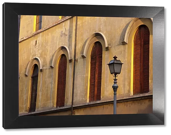 Italy, Tuscany, Lucca. Street lamppost and arched windows with wooden shutters. Date: 10-10-2010