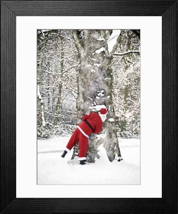 Framed Print : Father Christmas - in snow - behind tree Framed Print : Father Christmas - in snow - behind tree