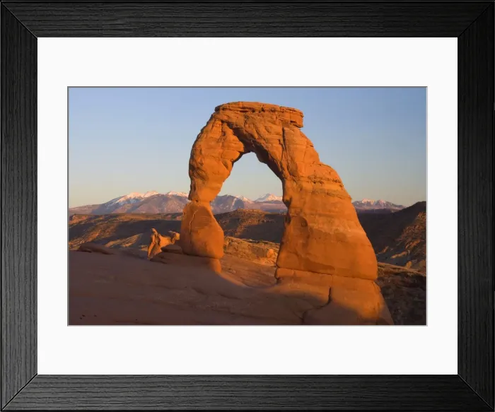 Framed Print : Delicate Arch - delicately sculptured sandstone arch standing in front of snow-covered Manti-La Sal Mountains on a slickrock slope. In late evening - Arches National Park, Utah, USA Framed Print : Delicate Arch - delicately sculptured sandstone arch standing in front of snow-covered Manti-La Sal Mountains on a slickrock slope. In late evening - Arches National Park, Utah, USA