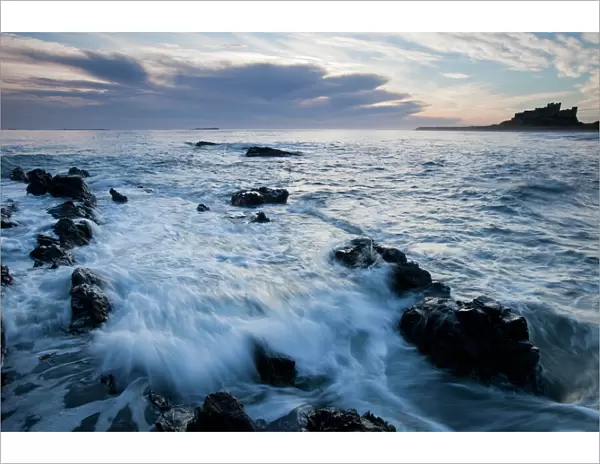 Bamburgh Castle - waves on rocky coastline before the castle - at dawn - Northumberland - England