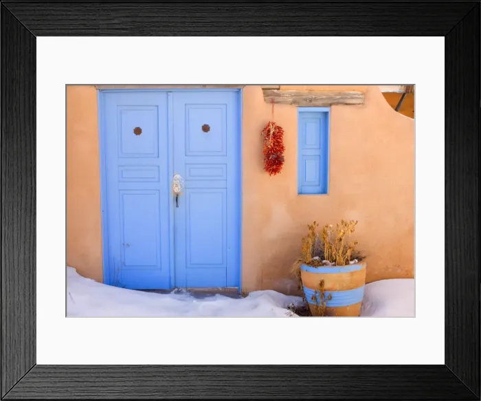 Framed Print : Adobe style house - simple beige coloured house in adobe style with a bright blue coloured door and a string of dried chilly peppers, called ristra, hanging from a beam. In winter - Rancho de Taos, New Mexico, USA Framed Print : Adobe style house - simple beige coloured house in adobe style with a bright blue coloured door and a string of dried chilly peppers, called ristra, hanging from a beam. In winter - Rancho de Taos, New Mexico, USA