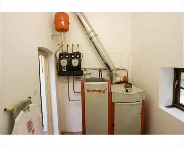 Boiler - Windhager Austrian wood pellet fired domestic biomass boiler produces heat for thermal store using small wood pellets supplied from a large external hopper installed in small cottage Cotswolds UK