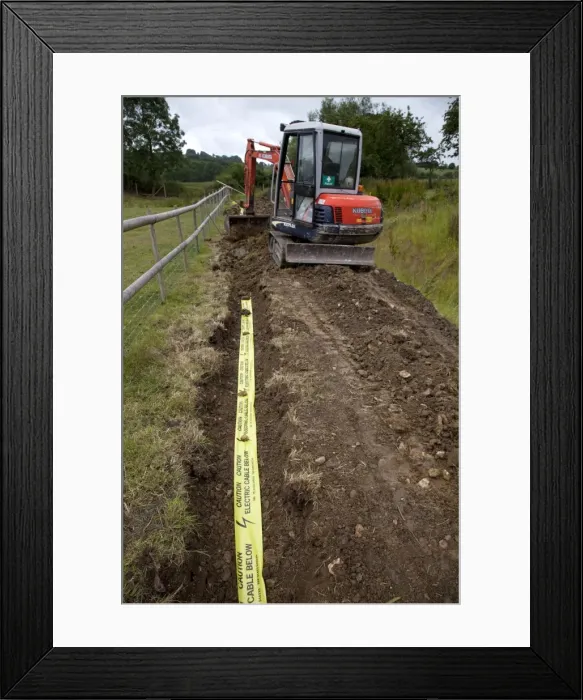 Framed Print : Kubota Digger - filling in trench with electric ducting and yellow warning tape - Cotswolds - UK Framed Print : Kubota Digger - filling in trench with electric ducting and yellow warning tape - Cotswolds - UK