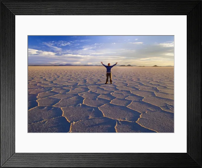 Framed Print : Traveller on Salar de Uyuni - a happy woman with raised hands stands amidst polygonal salt pattern on dried up salt lake at sunset - Salar de Uyuni - Altiplano - Bolivia - South America