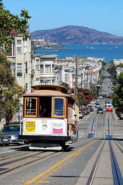 13132534. Street scene with a Cable Car tram and Alcatraz Prison island in San Franciso