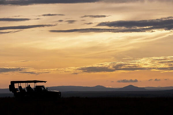 Africa, Kenya, Northern Serengeti Plains, Maasai Mara. Mara sunrise with safari jeep silhouette. Date: 30-10-2020