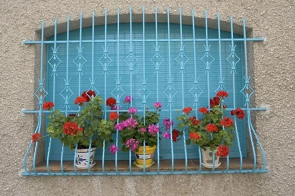 Attractive window display with blue railings and red geraniums, la Bastide-de-Serou, France
