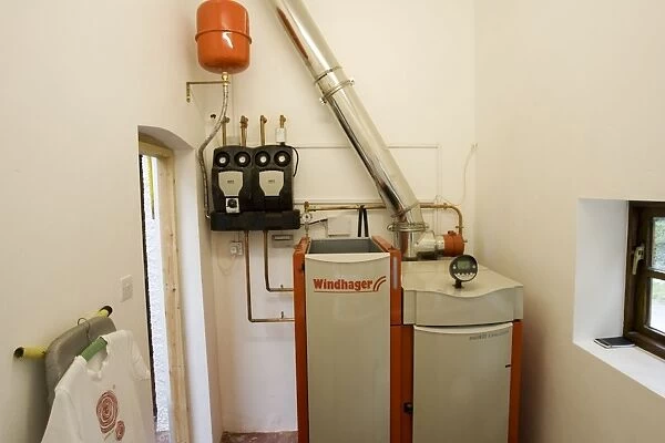 Boiler - Windhager Austrian wood pellet fired domestic biomass boiler produces heat for thermal store using small wood pellets supplied from a large external hopper installed in small cottage Cotswolds UK