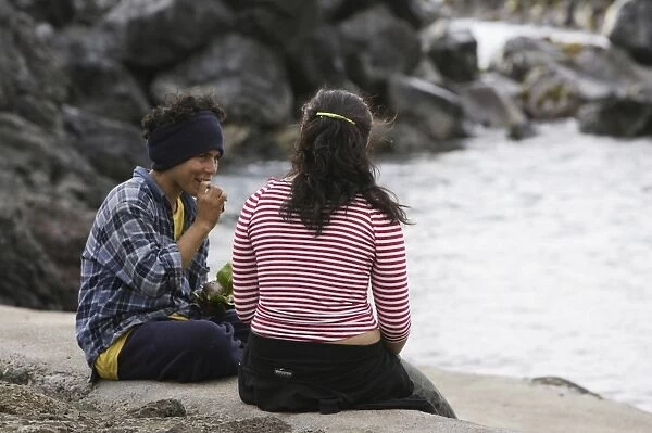 A boy and girl sitting by the sea eating ԣurantoլ