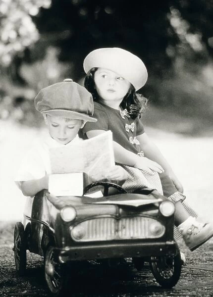 Children - boy and girl in toy car reading map