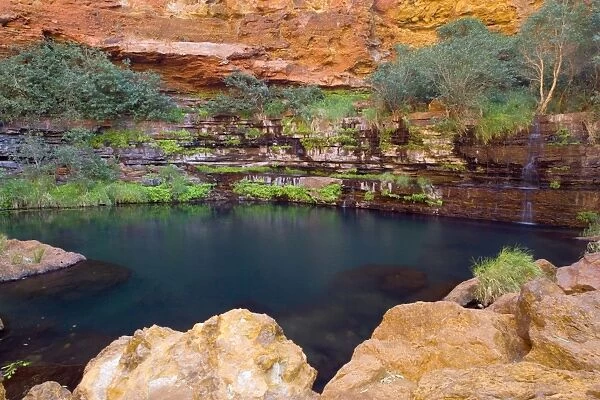 Circular Pool - water cascades down a steep, heavily with fern covered, terraced canyon wall into picturesque Circular Pool. The dark turquoise coloured water contrasts nicely with the bright red canyon walls
