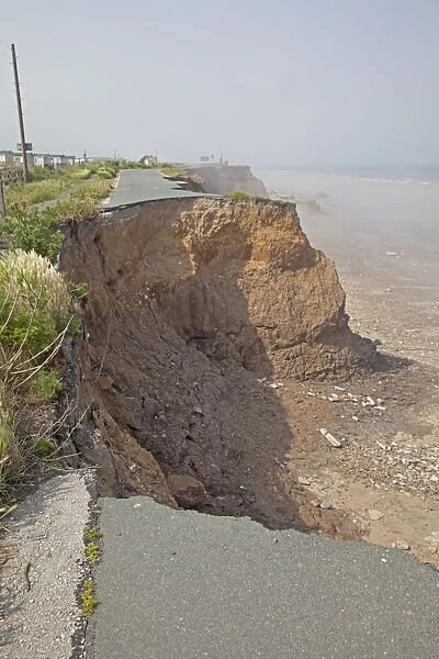 Collapsing tarmac road at cliff edge on coast road Skipsea East Riding of Yorskhire UK