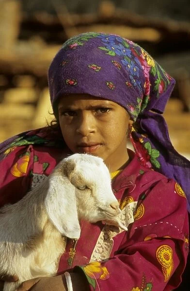 Egypt - a Bedouin girl cuddles a goat; a small