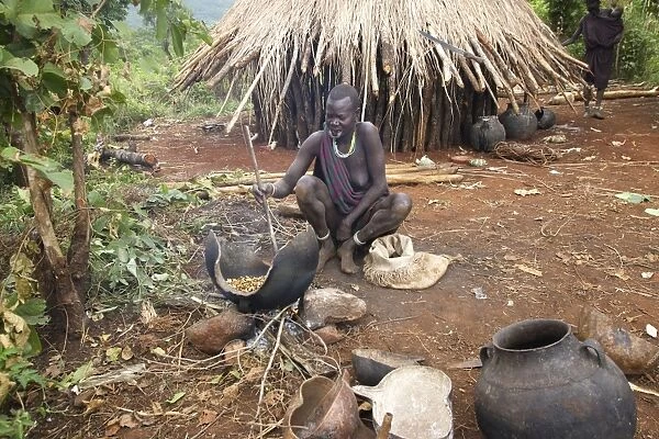 Ethiopia - woman fermenting beer outside hut