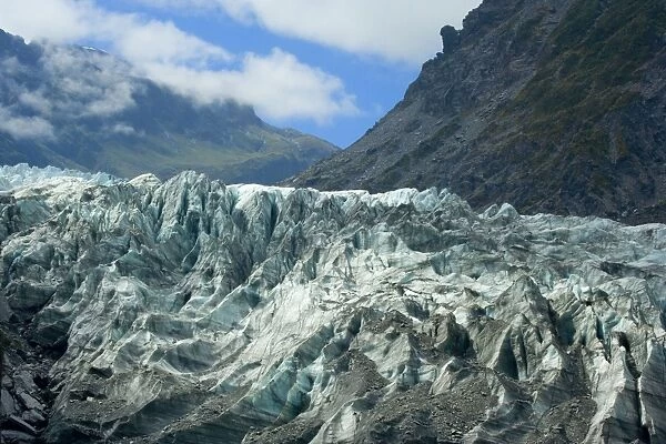 Fox Glacier river of ice cutting through glacial valley nestled amidst mountains covered by primeval rainforest Westland National Park, West Coast, South Island, New Zealand