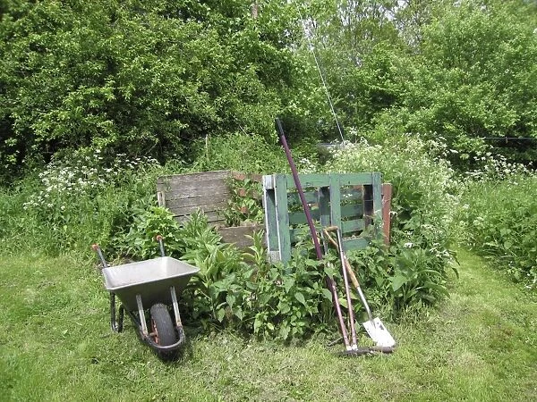 Garden compost area with wheelbarrow and tools