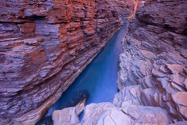Hancock Gorge - a stream is flowing down Hancock Gorge, surrounded by steep, red and very terraced cliffs. At this section the stream is quite deep which is the reason why the water has such an amazing shade of blue - Hancock Gorge, Hamersley Range