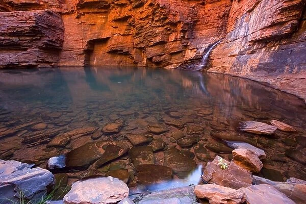 Handrail Pool - a waterfall flows into a hugh pool hidden within the steep, red and very terraced walls of Weano Gorge. The waterfall and walls are reflecting in the calm surface of the clear and very cold water - Weano Gorge, Hamersley Range