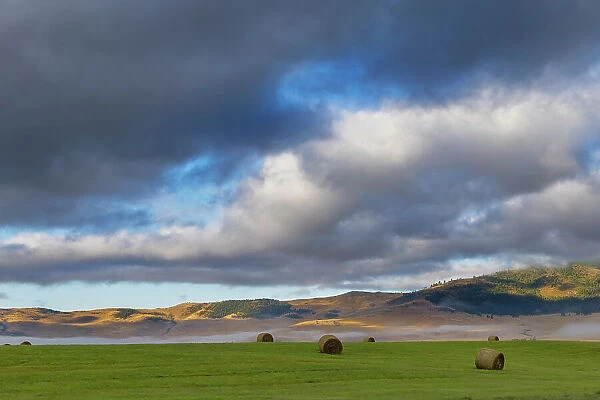 Hay bales in clearing fog with Salish Mountains in Lake County, Montana, USA Date: 28-08-2021