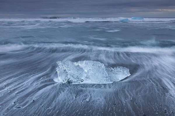 Ice and rushing waves on the beach in winter