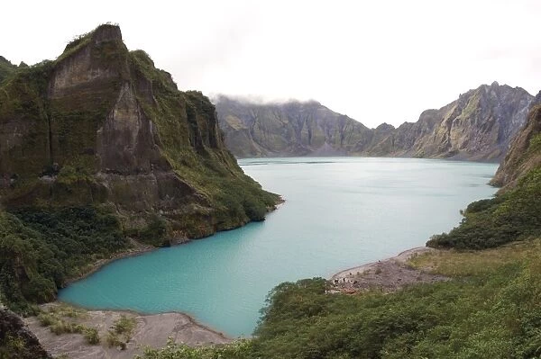 A lake, formed in a crater of volcano Pinatubo (the water level gradually rises over the years), erupted in 1992. The blue colour of water is due to a high salinity. A group of tourists prepares to paddle around