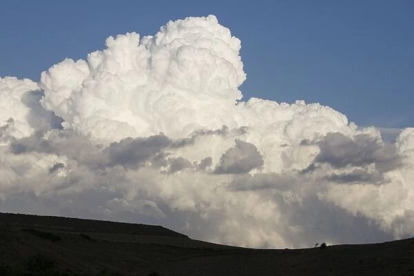 Low altitude billowing cumulus clouds on horizon looming above dark foreground Northern Spain