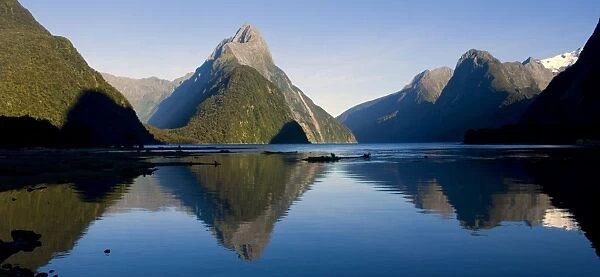 Milford Sound landmark Mitre Peak and surrounding mountains reflected in the calm waters of Milford Sound in early morning. Milford Sound is one of the, if not THE, most famous attraction in New Zealand