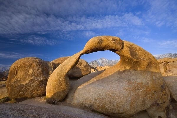 Mobius Arch - Lone Pine, one of the snow-capped mountains of the Sierra Nevada, seen through rock arch of red granite. In early morning - Alabama Hills Recreation Area, California, USA