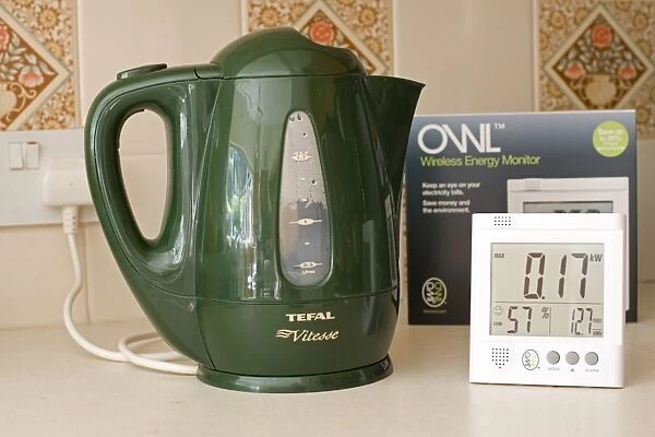 Owl energy monitor set to measure kW with green kettle turned off on kitchen worktop UK. Owl monitors formerly sold as Electrisave measure current eletricity use in either kW or carbon emissions as well as cost per hour
