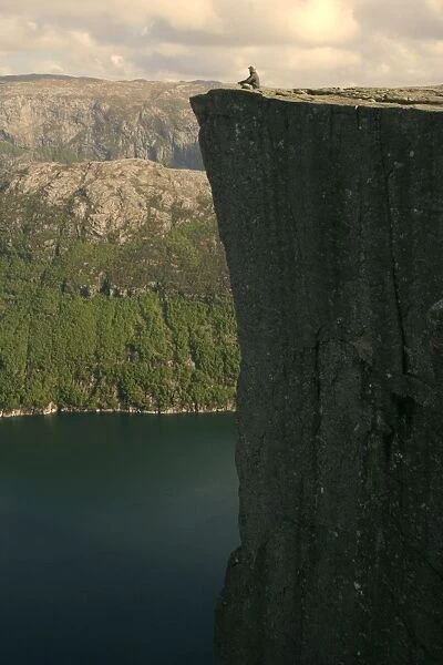 Preikestolen person meditating near the edge of rock pulpit Preikestolen with vertical drop of nearly 600 m clearly visible Preikestolen, Telemark, Norway