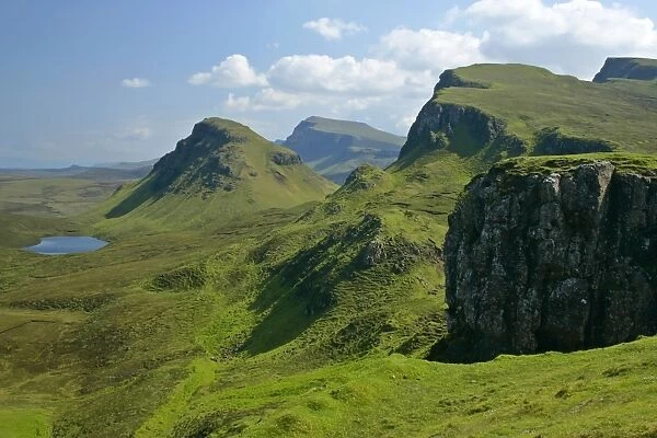 The Quiraing landscape lake and rolling velvet green slopes sprinkled with basaltic spikes of rock and cliffs Isle of Skye, Western Highlands, Scotland, UK
