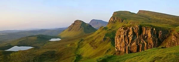 The Quiraing landscape lake and rolling velvet green slopes sprinkled with basaltic spikes of rock and cliffs at sunrise Isle of Skye, Western Highlands, Scotland, UK