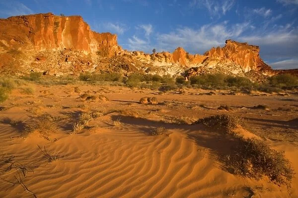 Rainbow Valley - colourful rock formation with bands of different coloured sandstone, from yellow to orange and rusty brown, ablaze in late evening light - Rainbow Valley, Simpson Desert area, Northern Territory, Australia