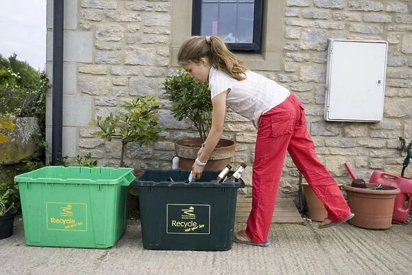Recycling - Young girl putting empty bottles in green bin Cotswolds UK Model released