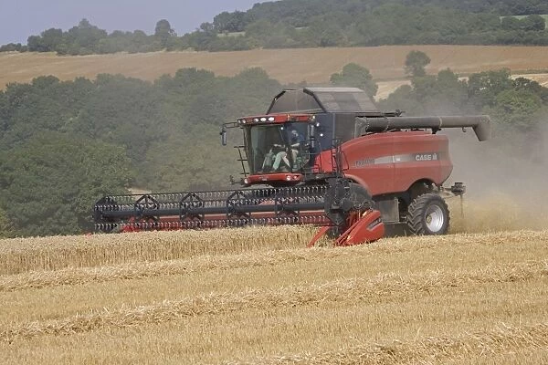 Red combine harvester working in Cotswolds near Winchcombe, UK