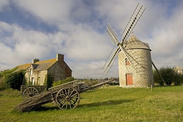 Restored French windmill with old wood cart in foreground near Cherrueiux Brittany France