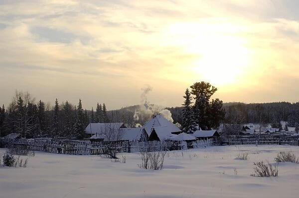 Russian village at midwinter sunset, a typical scene in North Ural Mountains; outskirts of the Vsevolodo-Blagodatskoye village, surrounded by coniferous forest; Russia, december. Ur39. 4477